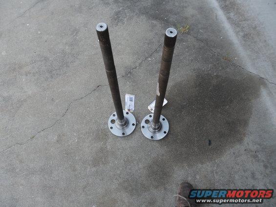 Two axle shafts with flanges on a concrete surface