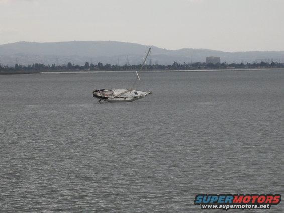 Sailboat listing in water, mast broken, hull damaged