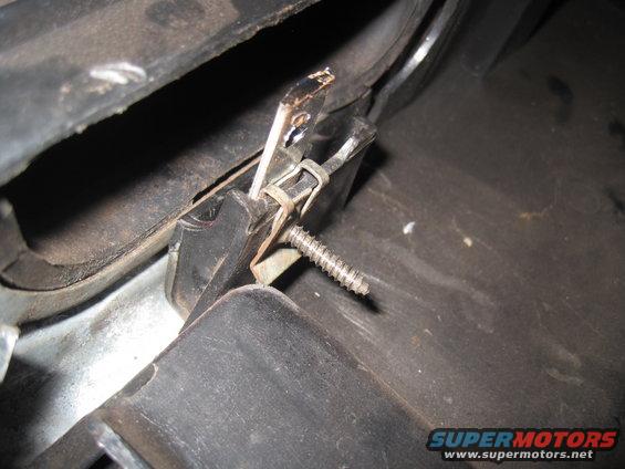 Close-up of a metal clip and screw mechanism inside a vehicle