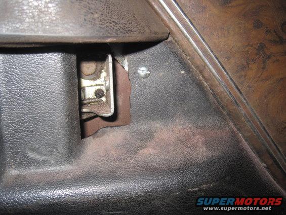 Close-up of a car's interior door panel showing a metal latch mechanism and a screw