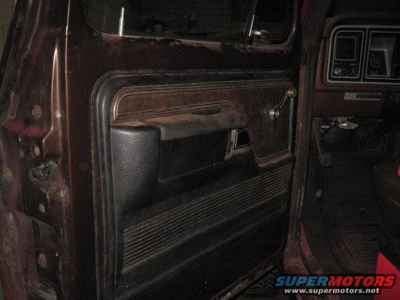 Brown and black car door panel with chrome handle and ribbed texture; dashboard visible