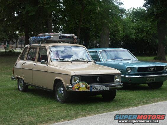 Tan Renault 16 station wagon with luggage on roof rack, parked next to a teal Ford Mustang