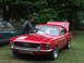 1977 Pontiac Trans Am - A man cleans the windshield of a red 1967 Ford Mustang parked next to a green car.