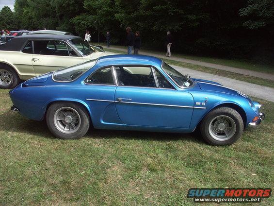 Blue coupe parked on grass next to a cream-colored car
