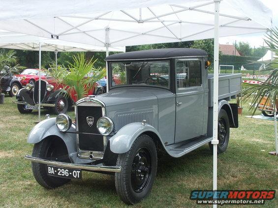 Gray Peugeot pickup truck with a black roof and bed, parked on grass under a white tent