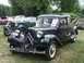 1977 Pontiac Trans Am - A classic black Citroën Traction Avant is displayed at an outdoor event with other vintage vehicles in the background.