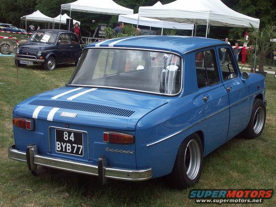 Blue sedan with white racing stripes on the roof and trunk, chrome bumper, and license plate BYB77