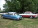 1977 Pontiac Trans Am - Two classic cars, a blue Citroen DS and a two-tone sedan, sit on a grassy field under trees.