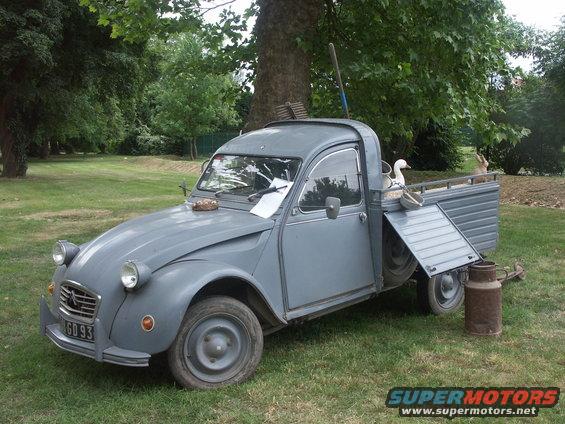 Gray Citroën 2CV pickup truck parked on grass with a duck in the bed