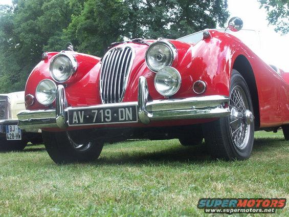 Red vintage convertible with wire wheels and chrome grille, front view. License plate AV-719-DN