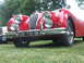 1977 Pontiac Trans Am - A red vintage convertible is parked on grass, with another vehicle partially visible to its left.
