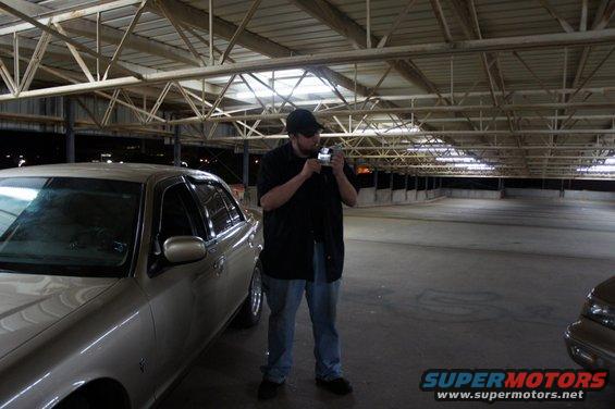 guy with a camera in front of a car in an empty parking garage