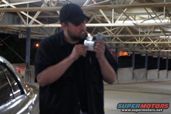 Man lighting cigarette in front of a silver car