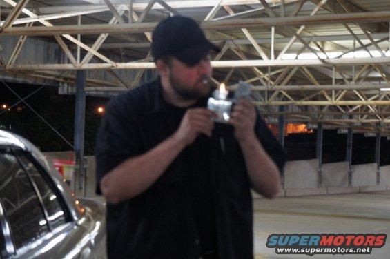 Man in black shirt and cap lighting a cigarette with a lighter