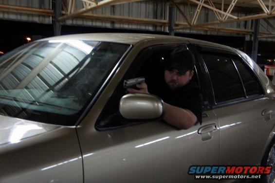 Man with gun in side view of 2000 Mercury Grand Marquis