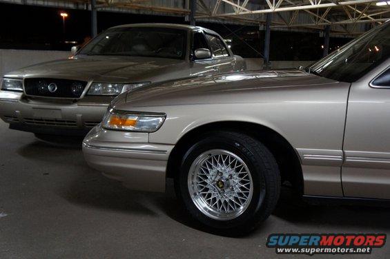 Two tan 2000 Mercury Grand Marquis sedans parked indoors, front quarter view of the closest car