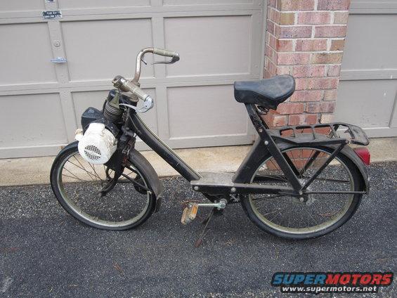 Black moped with a white headlight cover and a rear rack