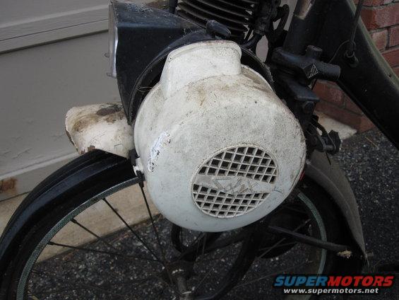 White engine cover with a grid pattern and a logo on a moped