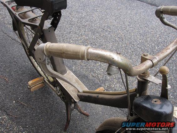 Close-up of a vintage moped's handlebars, pedals, and seat