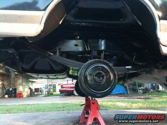 Undercarriage of vehicle on jack stands, showing leaf springs and drum brake