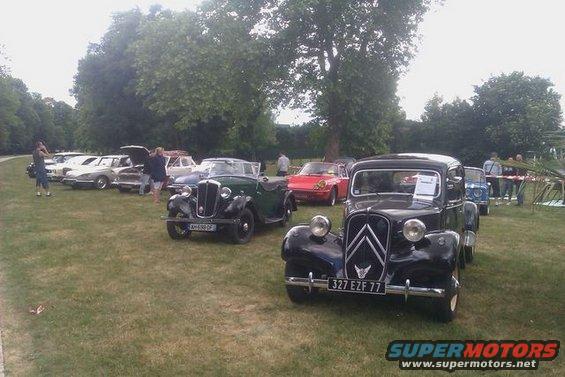 Black Citroën Traction Avant with license plate 327 EZF 77 parked on grass with other vintage cars