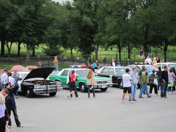 Several police cars parked in a lot, one with hood open