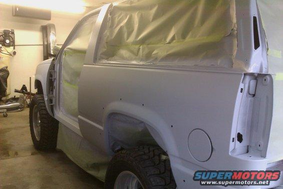 1994 Chevrolet Blazer body in primer, doors open, masked for paint. Rear quarter panel shows fuel door and taillight housing