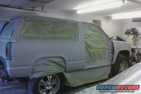 SUV covered in masking paper and tape, ready for paint. Door is open