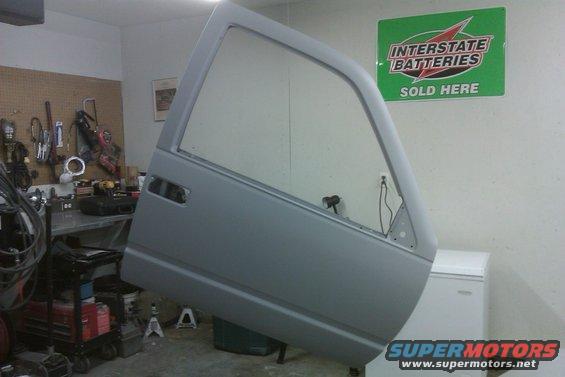 Gray vehicle door hanging in a garage, tools on wall behind it, Interstate Batteries sign on wall