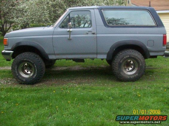 Gray Ford Bronco with a black top, lifted suspension, and off-road tires, seen from the side