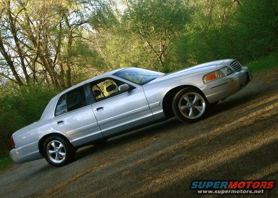 Silver 2000 Ford Crown Victoria sedan parked on a dirt road with trees in the background