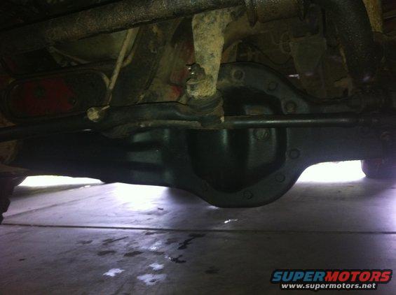 Underside of a vehicle showing a differential, suspension arms, and a red taillight