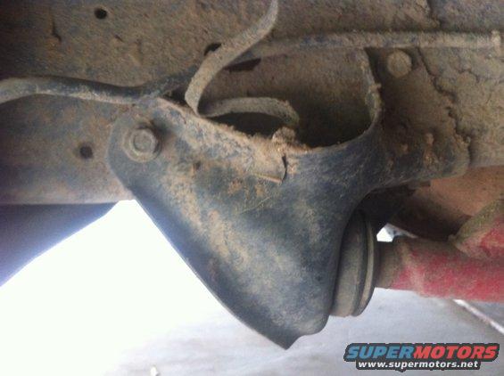 Close-up of a dirty vehicle suspension part with a red shock absorber visible