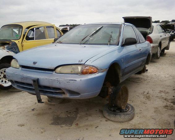 1991 Ford Festiva in junkyard, missing wheels, light blue paint