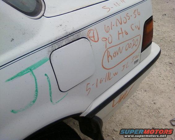 White car's rear quarter panel with graffiti and handwritten notes, including 'ROW 0020'
