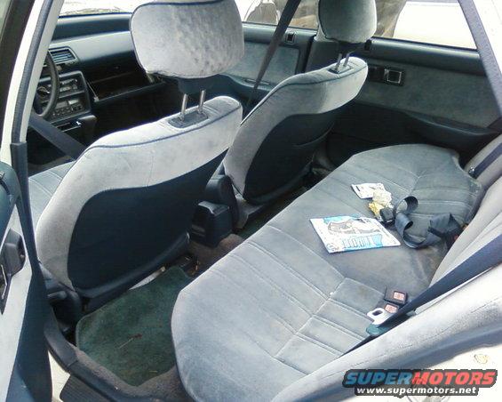 Interior view of a car with grey cloth seats and a magazine on the back seat