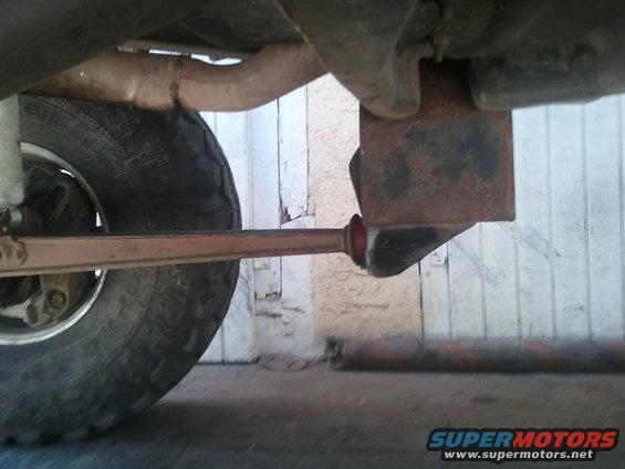 Undercarriage of a vehicle showing a tire, suspension components, and exhaust pipe