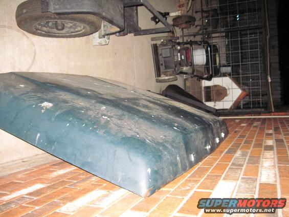 hood of a vehicle, spare tire, and engine components on a brick patio
