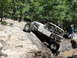 1967 Ford Mustang - A custom-built off-road buggy navigates a challenging rocky terrain with spectators nearby.