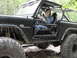 1967 Ford Mustang - A woman sits in the driver's seat of a modified black Ford Bronco off-road vehicle.