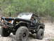 1967 Ford Mustang - A woman drives a heavily modified black Ford Bronco with large off-road tires through a wooded trail.