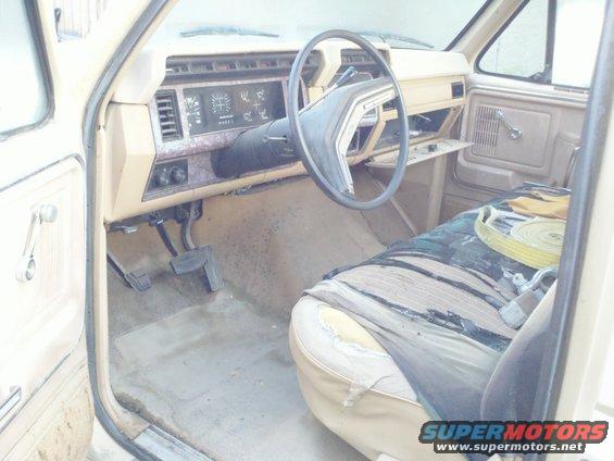 Tan interior of a truck with a torn seat cover and a steering wheel. The dashboard has gauges and vents