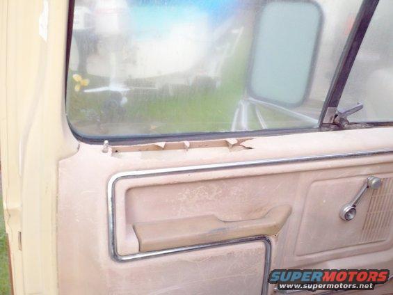 Interior door panel with armrest and window crank. Peeling trim above window