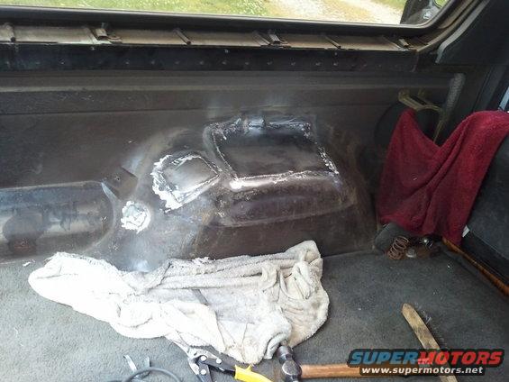 Interior floor of vehicle with welded patch repairs and tools. A red towel hangs on the side