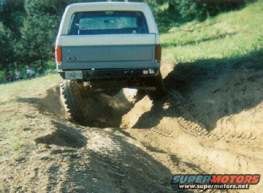 1988 Ford Bronco driving on a dirt trail, rear view