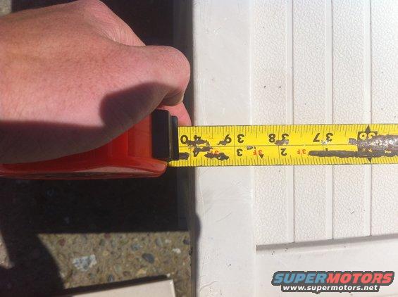Hand holding a tape measure showing 39 inches against a white ribbed panel