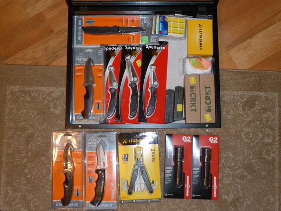 Collection of knives, multi-tool, and flashlights in packaging