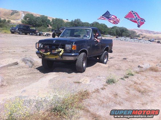 Black Ford F-150 pickup truck with American and Confederate flags