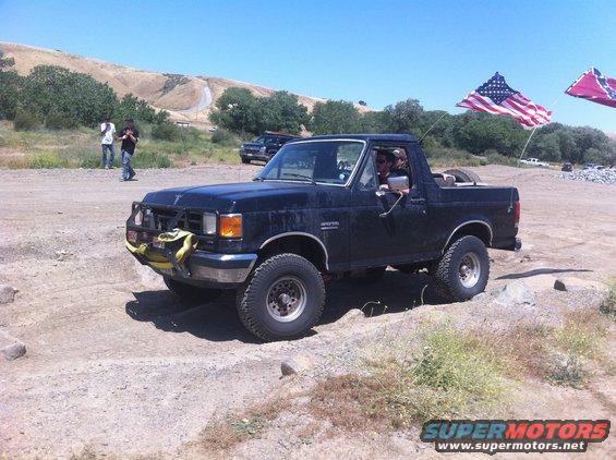Black 1990 Ford Bronco with brush guard driving off-road