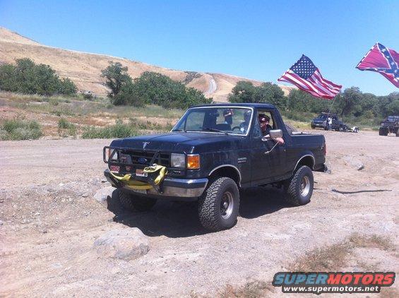 1990 Ford Bronco with bull bar and flags driving off-road